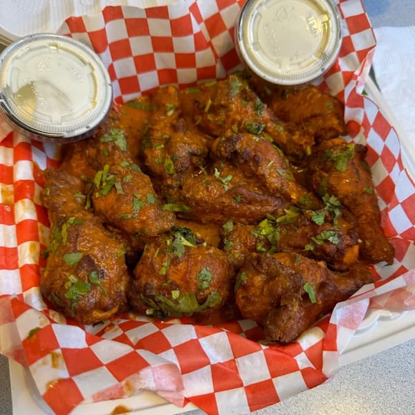 Mighty Munch Mtn Curry Pizza's chicken wings, coated in a rich curry sauce and garnished with fresh cilantro.