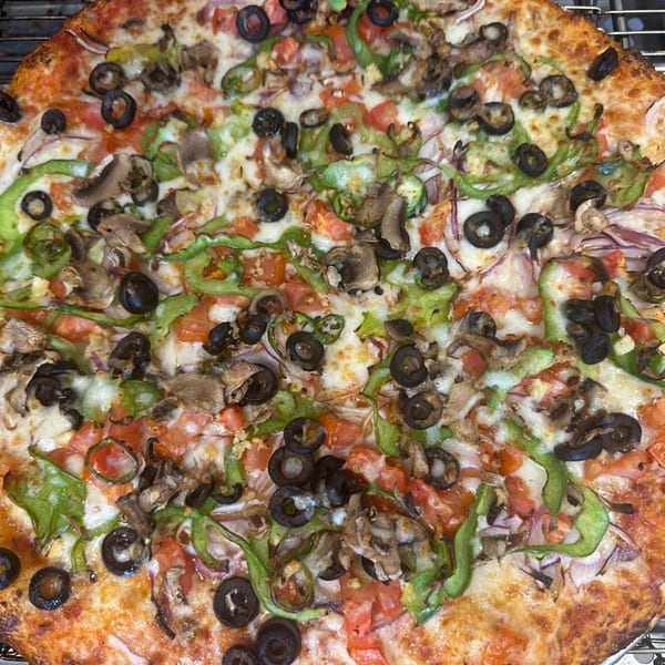 A Mighty Munch Mtn Curry Pizza, topped with green peppers, black olives, mushrooms, and tomatoes.