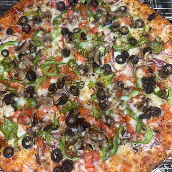 A Mighty Munch Mtn Curry Pizza, topped with mushrooms, black olives, green peppers, and tomatoes.