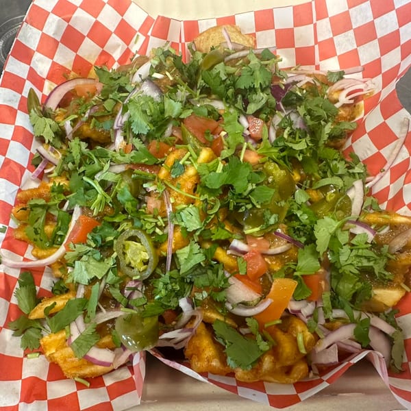 Mighty Munch Mtn Curry Pizza's loaded fries with cilantro, red onions, tomatoes, and jalapeños.