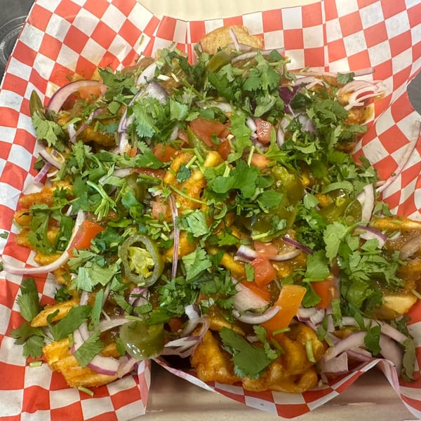 Mighty Munch Mtn Curry Pizza's Indian-style fries topped with cilantro, red onions, tomatoes, and jalapeños.
