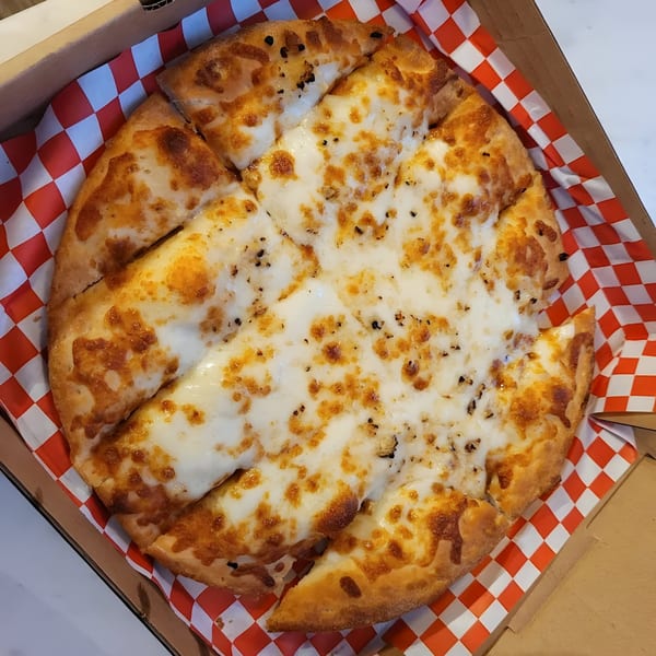 A Mighty Munch Mtn Curry Pizza garlic cheese bread, cut into slices, in a box with red and white checkered paper.