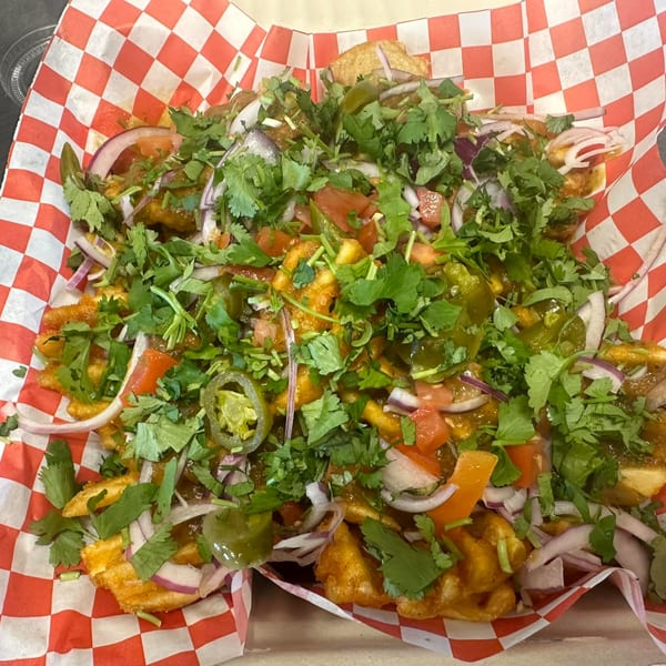Mighty Munch Mtn Curry Pizza's loaded fries with red onions, tomatoes, cilantro, and jalapeños.